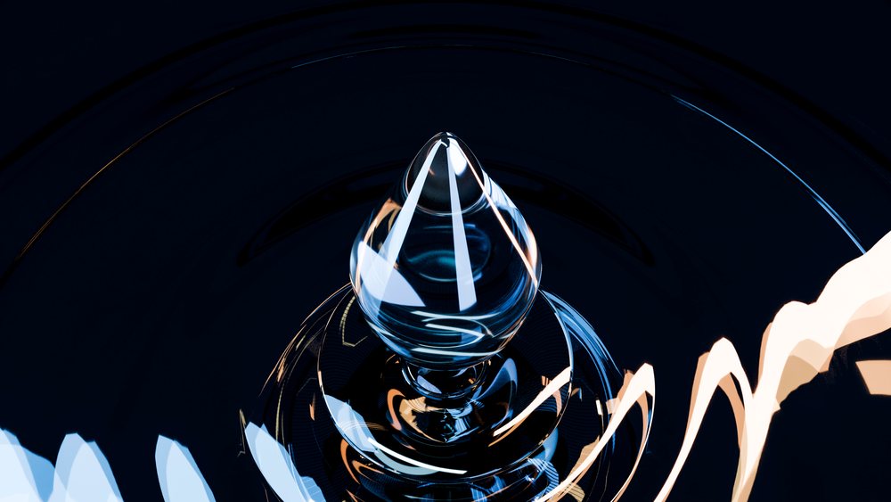 Close-up image showing a teardrop-shaped water droplet suspended above a dark water surface with circular ripples and bright light reflections.