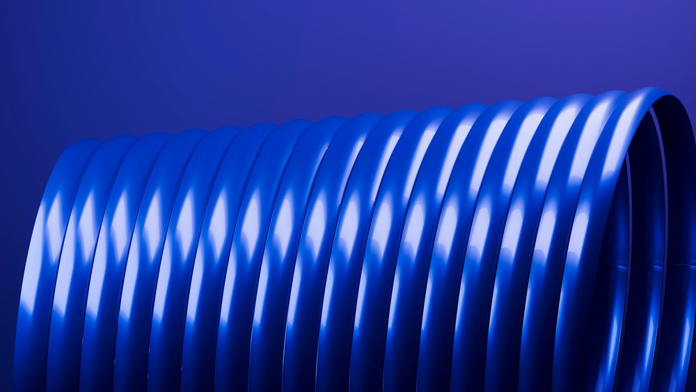 Closeup of blue curved tubular coils with reflective surfaces against a blue background in a studio setting.