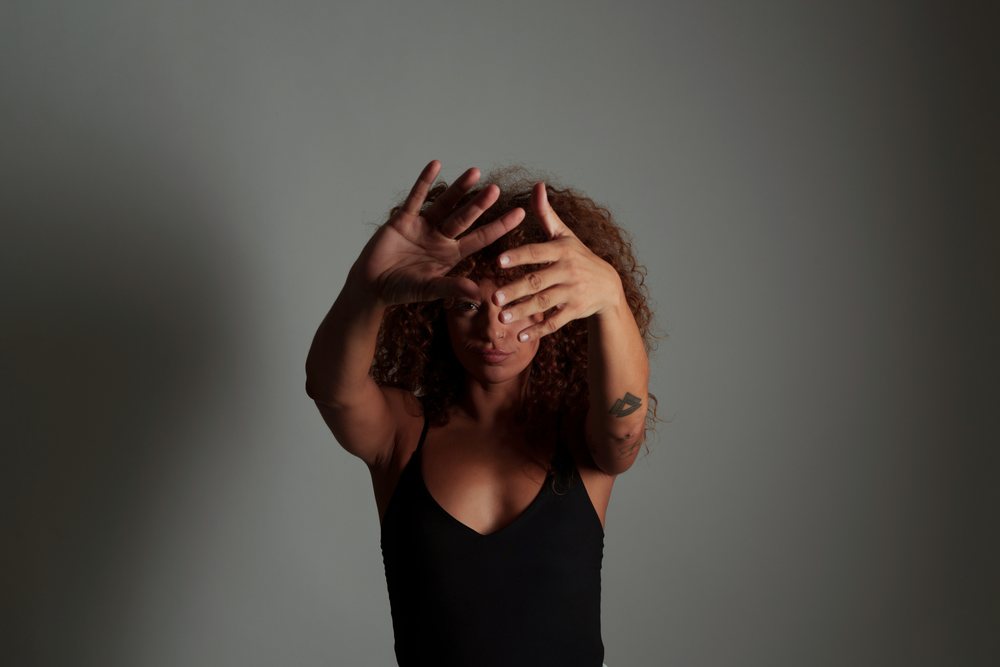 Woman with curly red hair and tattoos poses expressively in a studio, Malaga, Spain.