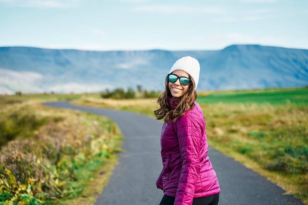 A white woman walking on a nature path with mountains