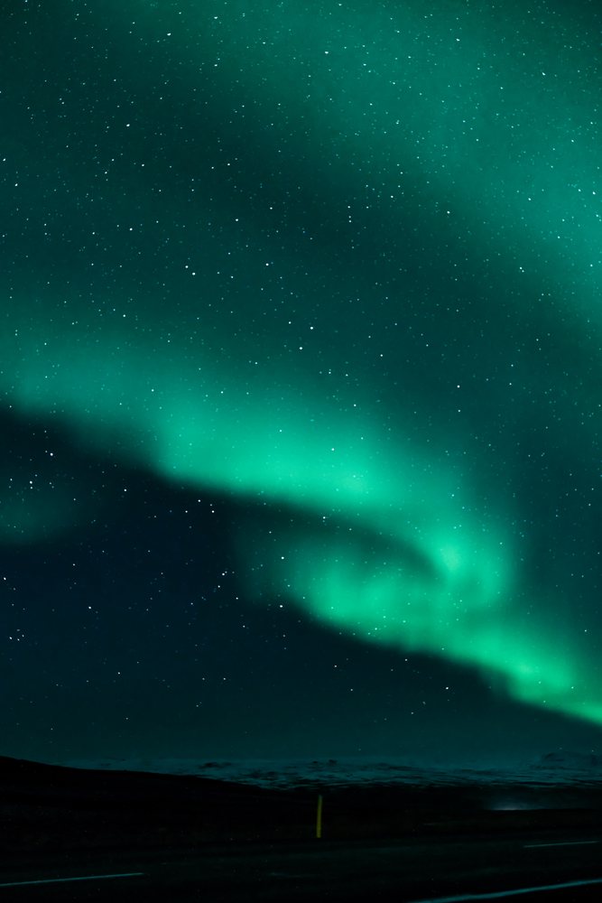 The northern lights glow vividly over a dark night sky