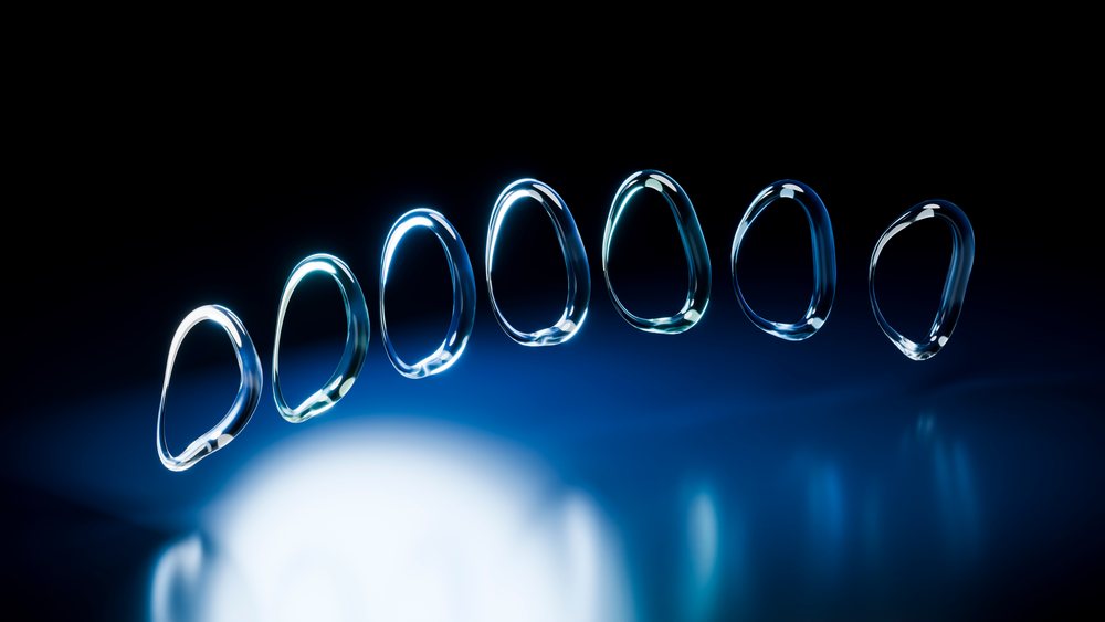 Blue-lit water droplets aligned on a reflective surface against a black background.
