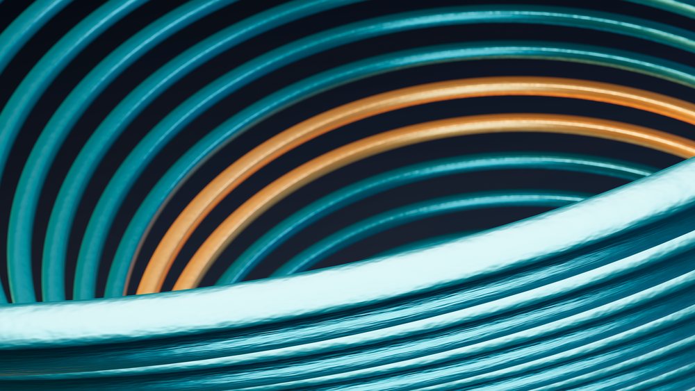 Coiled blue and orange rubber hoses arranged in a spiral pattern as outdoor watering equipment.