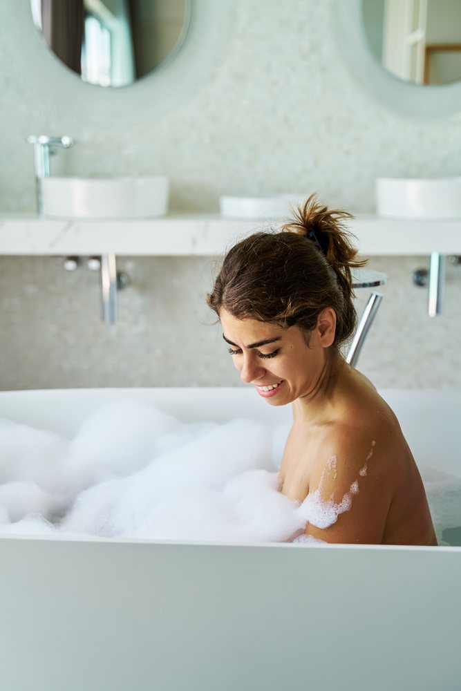 A woman enjoys a bubble bath while relaxing in a modern bathroom in the, Maldives.
