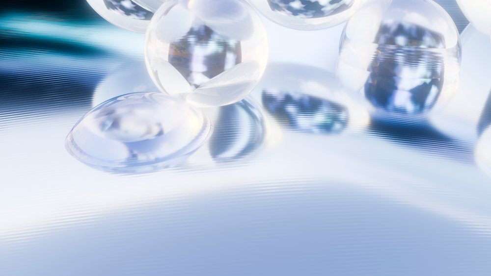Transparent spheres reflect light on a smooth reflective surface in an abstract, minimalist arrangement with soft lighting and a blurred background.