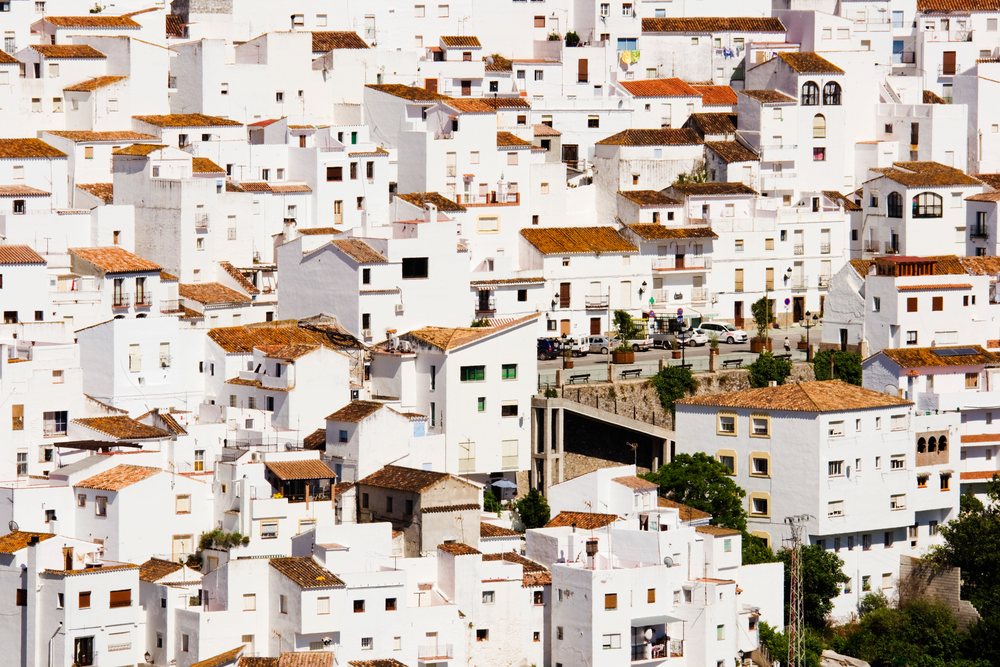 Sunlit white residential buildings with terracotta roof tiles on a hillside in the town of Casares, Andalusia, Adnalusia, Spain.