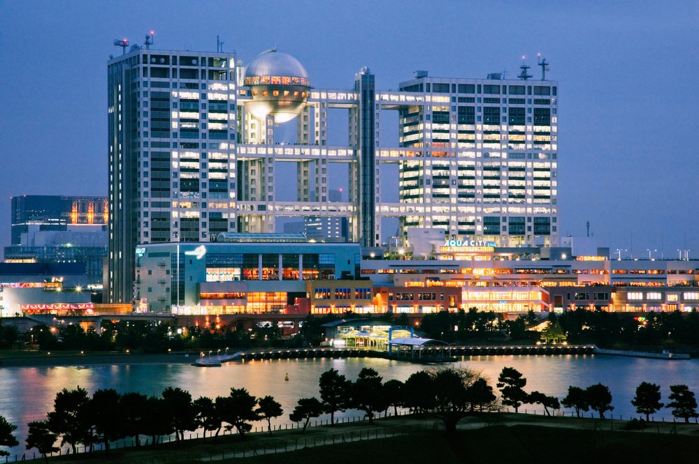 Night view of Aqua City and Fuji TV Building brightly illuminated over the waterfront in Odaiba, Tokyo, Japan.