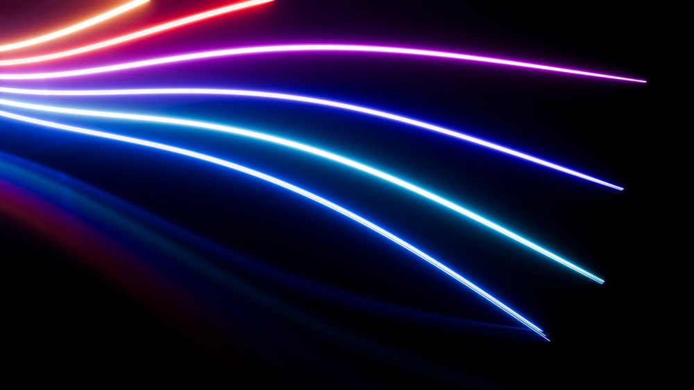 Glowing neon light trails in blue, purple, and pink curve against a dark background in digital art.