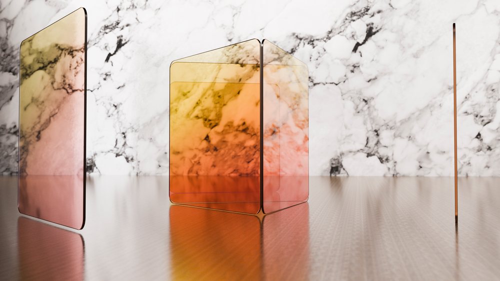 Colored transparent glass panels and a glass cube arranged on a reflective metallic surface with a marble wall background.