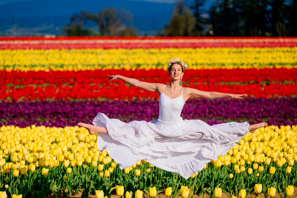 Ballet dancer leaps joyfully in a vibrant tulip field in the USA during spring.