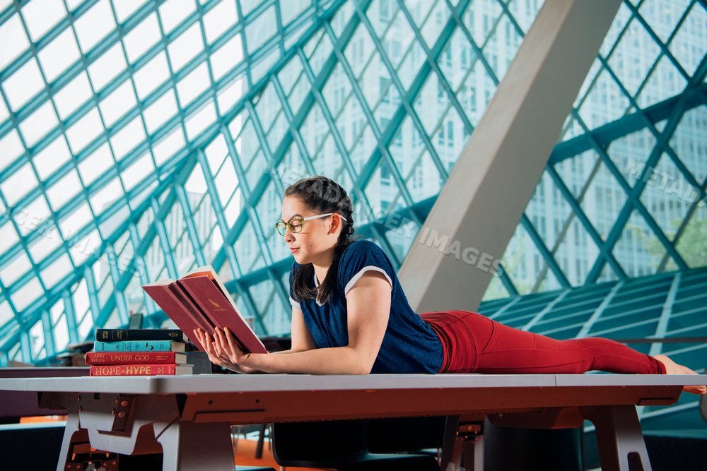 Woman reading book inside a modern public library in a library
