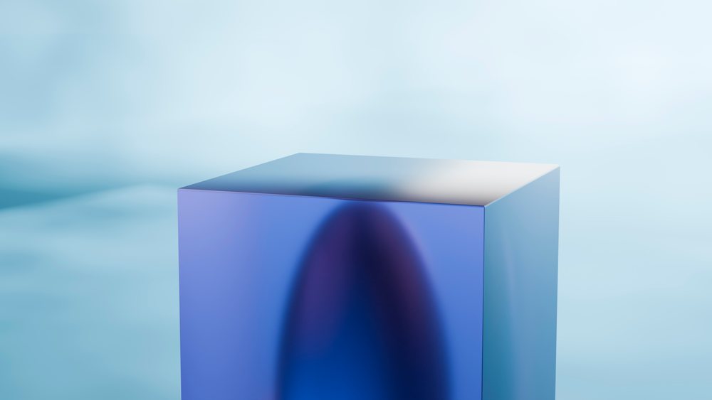 Blue translucent cube with smooth surface and gradient colors in a minimalist abstract setting under soft studio lighting.