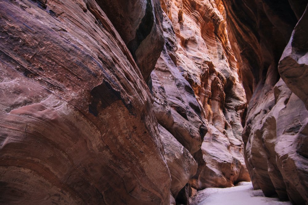 Natural rock formations form a narrow slot canyon with a sand path, Buckskin Gulch, Utah, USA.