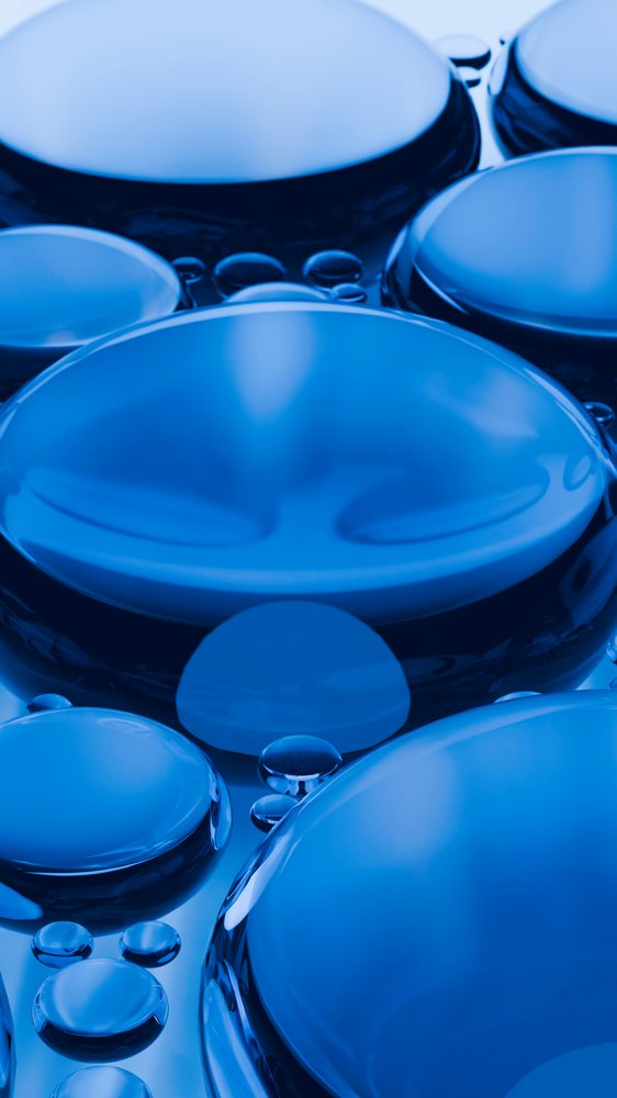 Close-up macro photograph showing multiple round blue water droplets exhibiting surface tension and clear liquid reflection.