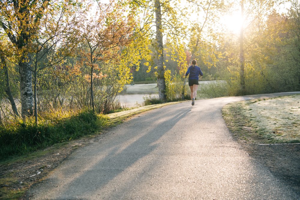Runner jogging on a paved park path in morning sunlight, Bainbridge Island, Wa, USA.