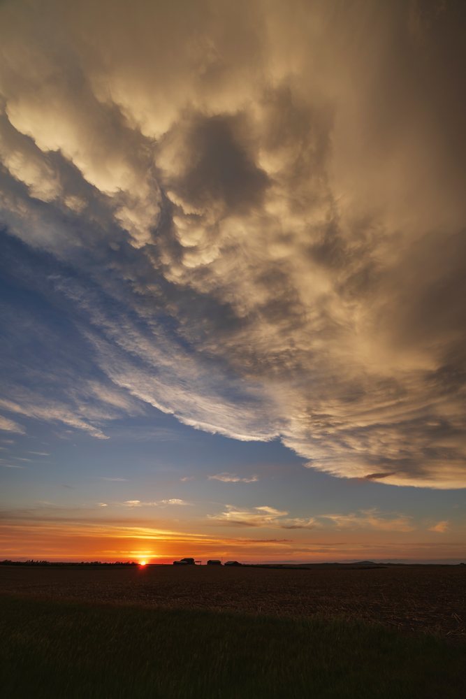 Post-Frontal Sunset with storm clouds over open agricultural fields and silhouetted farm buildings, Storm Chasing, Weather, Environmental, Winner, South Dakota, USA.