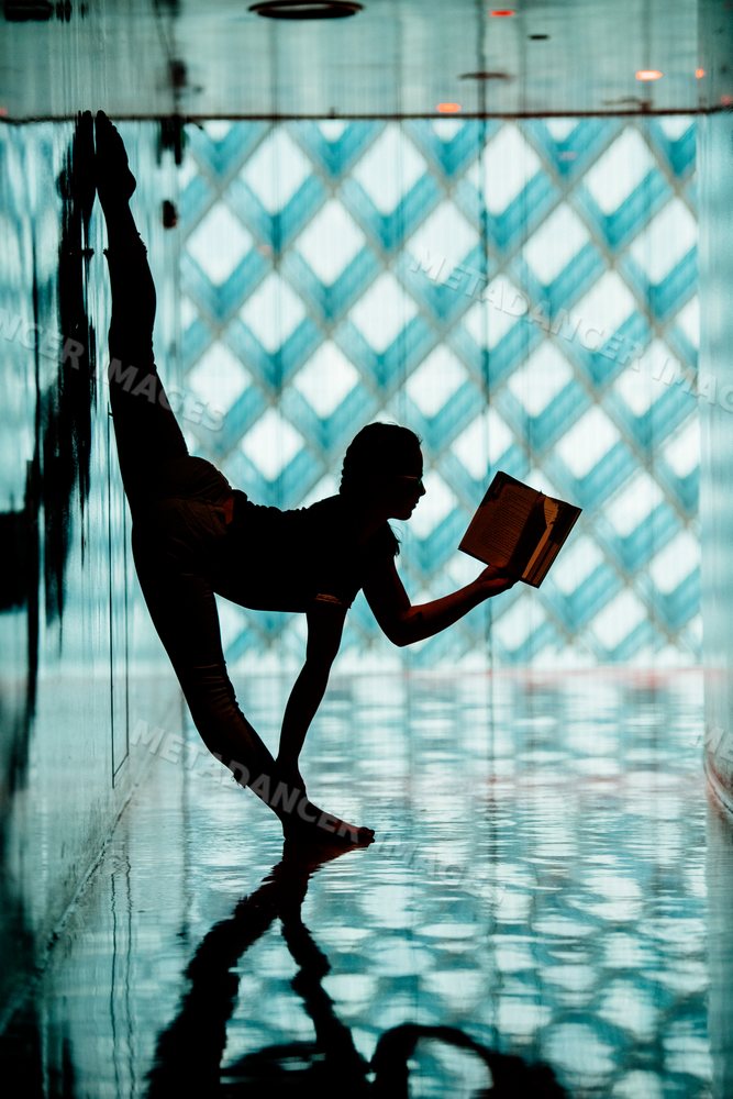 A person reads a book while doing yoga stretching