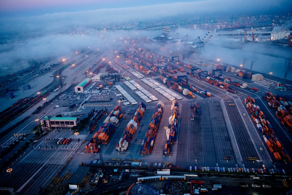 Container port and shipping terminal at the Port of Long Beach with rows of freight containers and cranes seen in early morning fog, CA, USA.