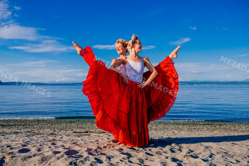 Two white women performing partner acrobatics on a beach in WA, USA