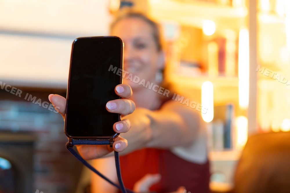 A woman shows a device screen indoors in a living room in Verdun