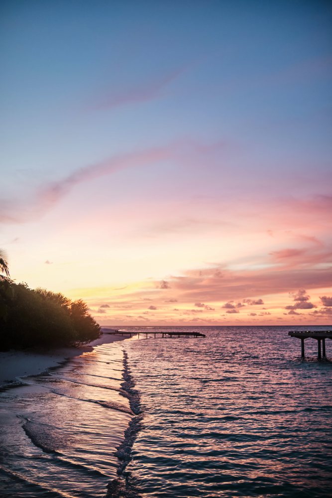 A tranquil sunset over a beach with waves and piers in a beach