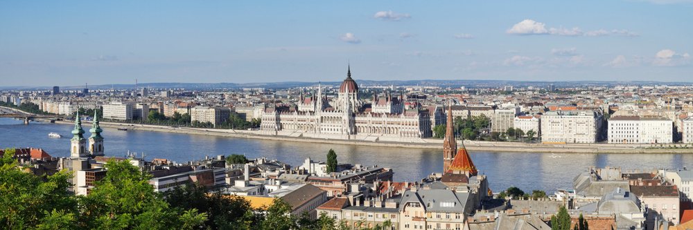 Panoramic cityscape of Budapest showing the parliament building along the Danube River under blue sky, Hungary.