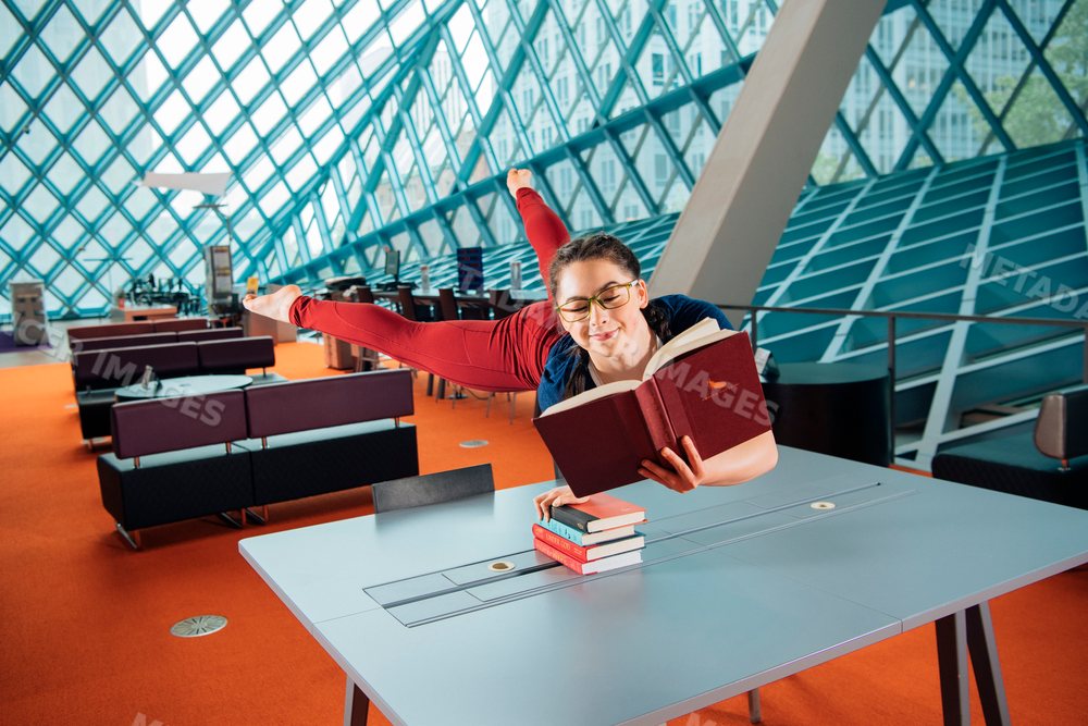 A woman reading a book while balancing on a table