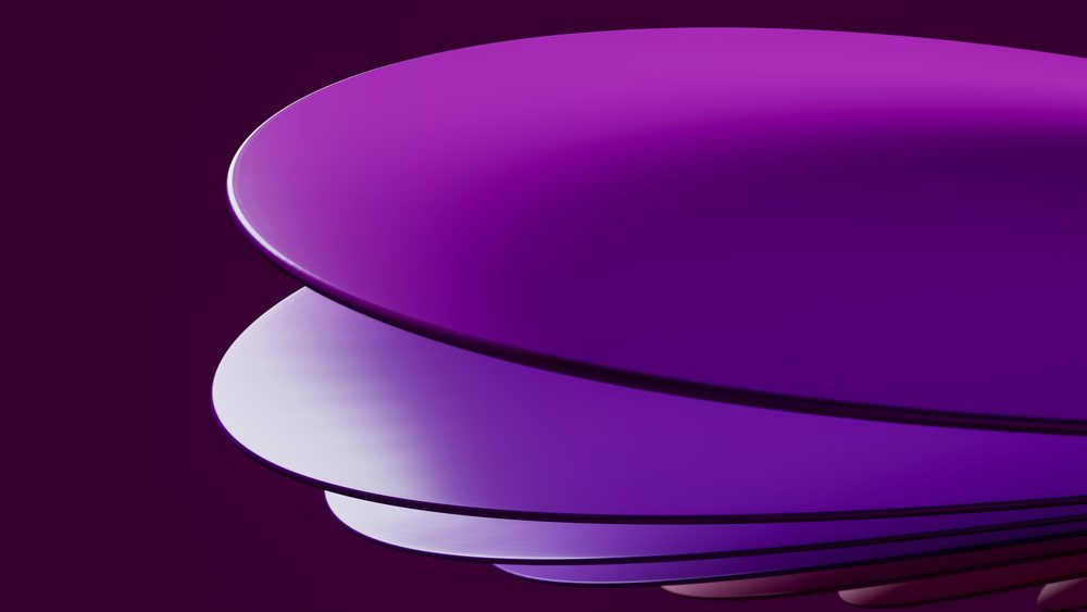 Glossy purple round plates with raised edges neatly stacked against a matching purple background in a studio setting.