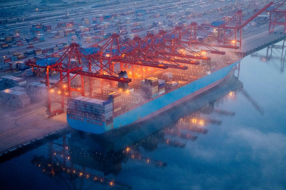 Container ship docks at port terminal with cranes loading shipping containers, Port of Long Beach, CA, USA.