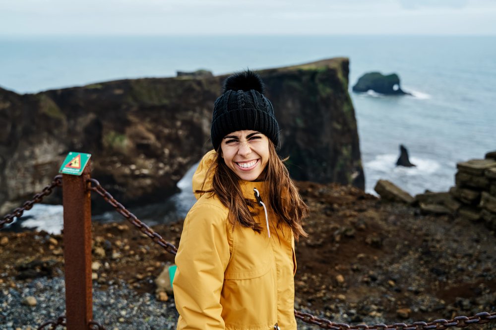 A white woman smiles on a scenic coastal cliff