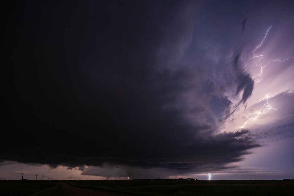 Tornado touches the ground with visible Lightning bolts flashing during a Supercell storm at night in the Great Plains, Lisbon, North Dakota, USA.