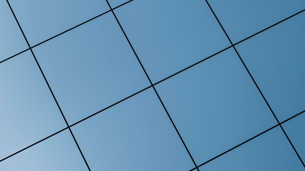 Modern building facade with blue glass panels forming a geometric pattern reflecting the sky.