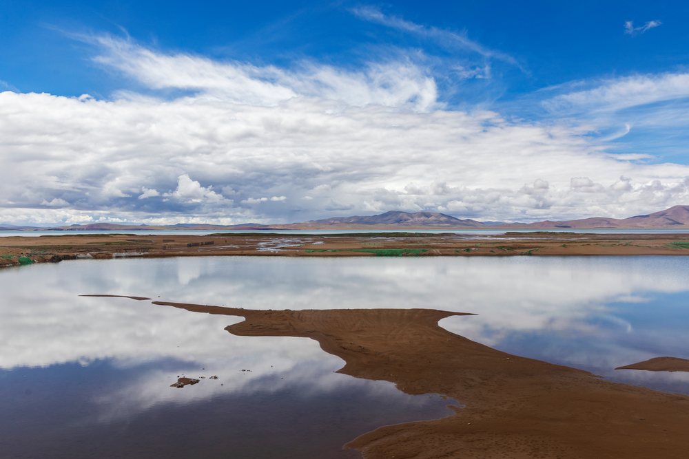 Lake Kuona reflects clouds and surrounding mountains, Amdo County, Autonomous Region of Tibet.