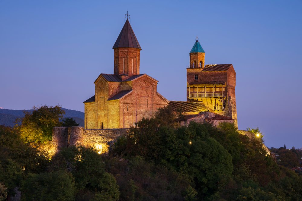 Gremi Monastery on a hillside surrounded by trees illuminated at Dusk, Sighnaghi, Georgia.