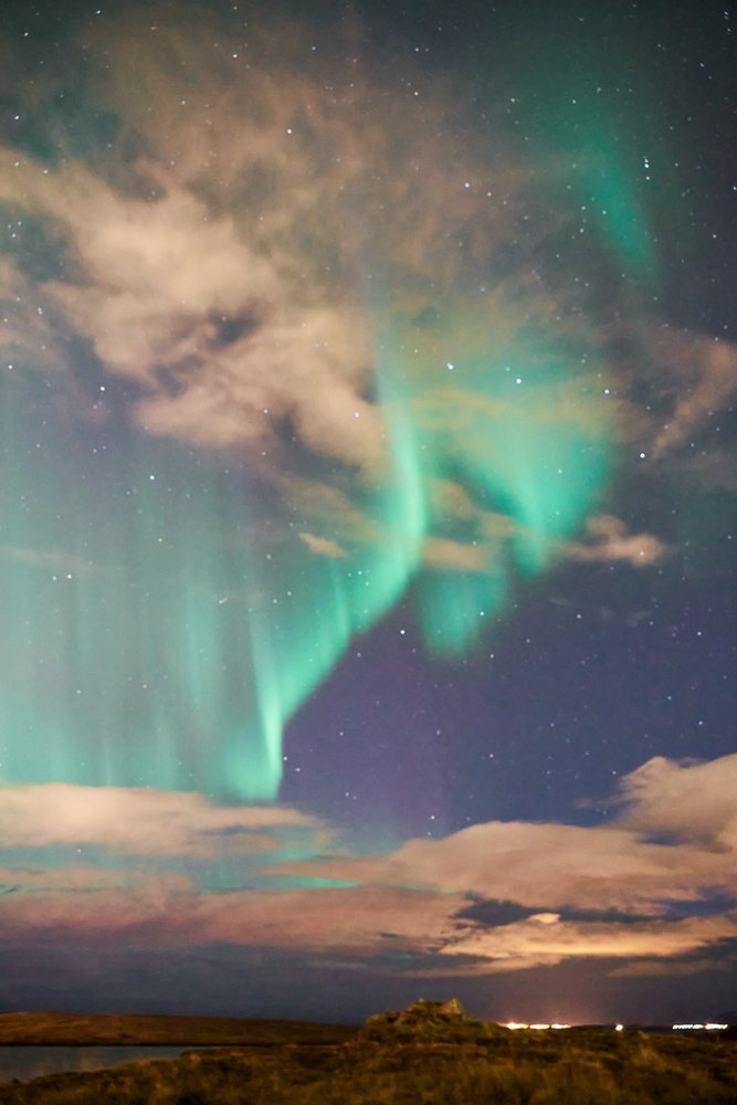 The northern lights illuminate the night sky over the landscape