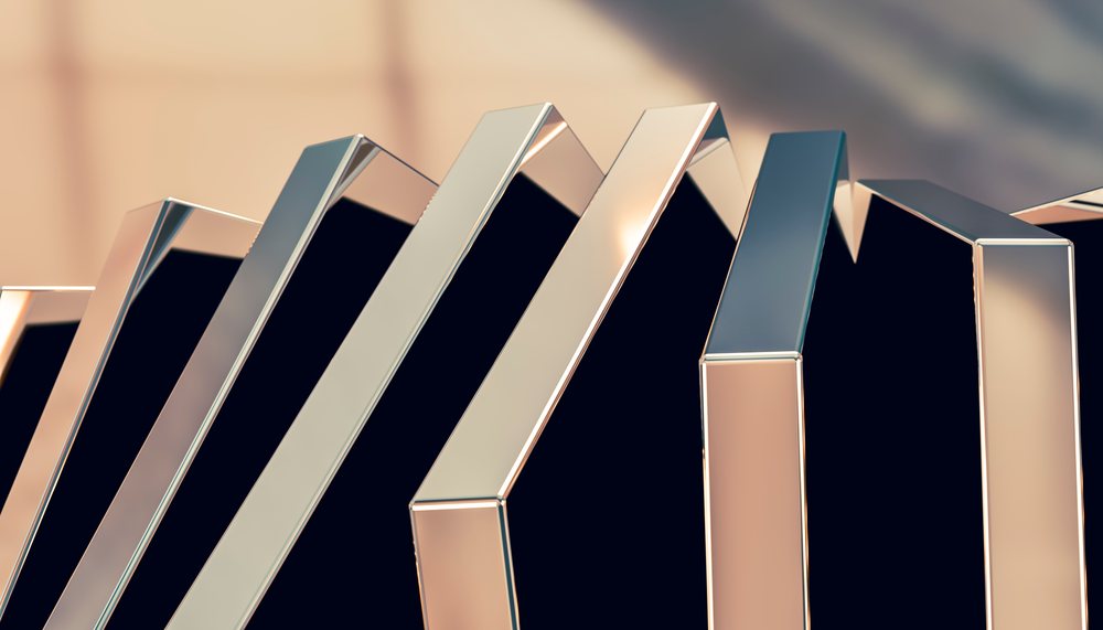 A close-up of silver metallic domino pieces arranged in a tilted chain formation on a black background.
