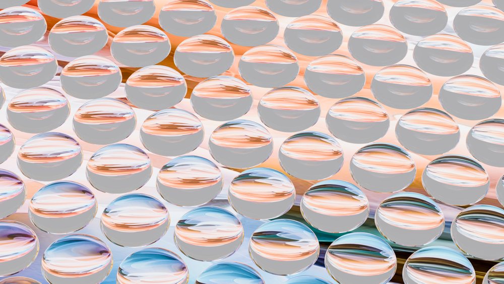 Close arrangement of transparent water drops forming a pattern that reflects and refracts colorful light against a gradient background.