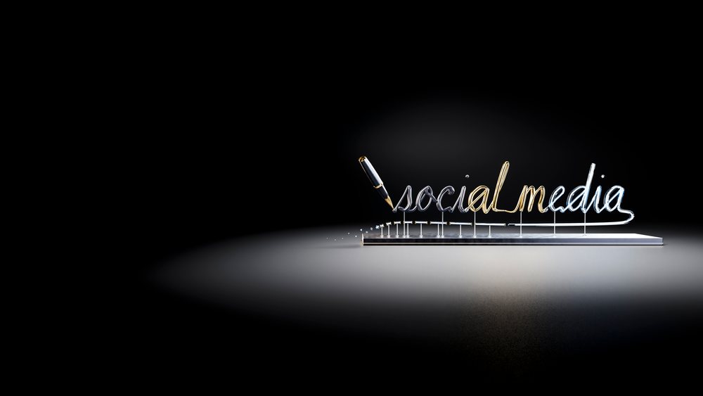 Metallic stylized social media script on a stand with a pen poised to write.
