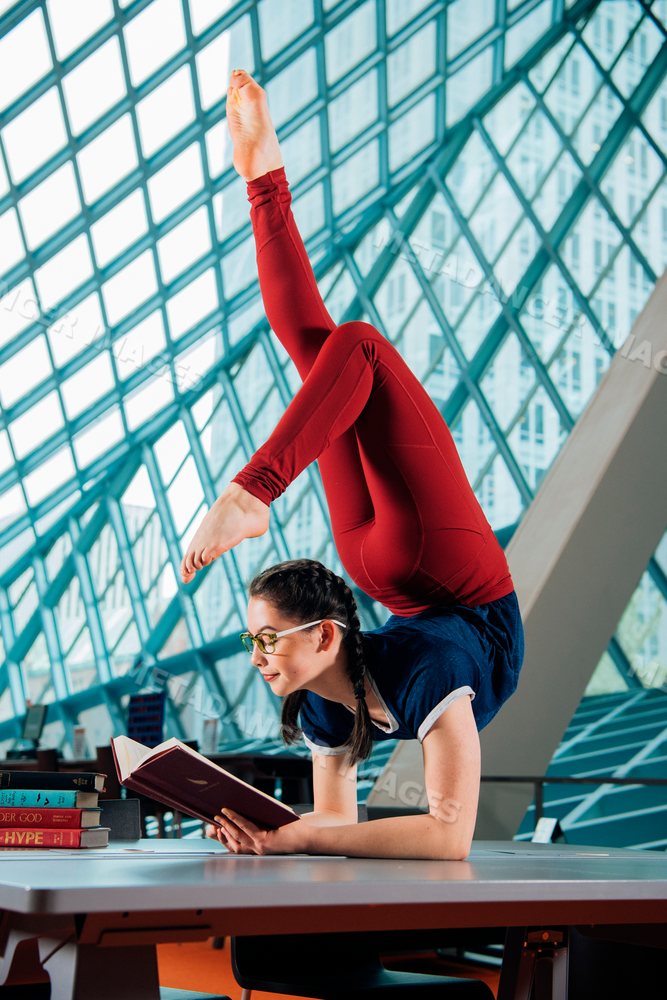 A young woman reads a book while balancing