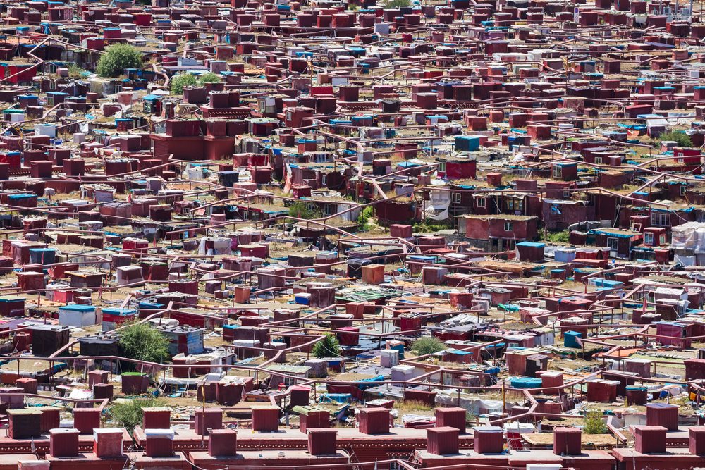Dense cluster of Tibetan Nun's Meditation Huts with red small houses and flat roofs on a hillside, Kham Tibet, Baiyu, Sichuan Province, People's Republic of China.