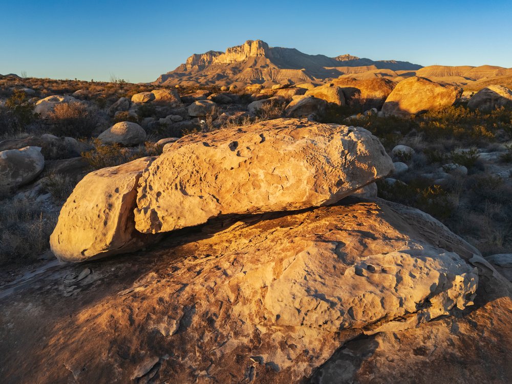 Boulders and dry desert vegetation under blue sky with El Capitán mountain in Guadalupe Mountains National Park, landscape, wildlife, Guadalupe Mountains NP, Texas, USA.