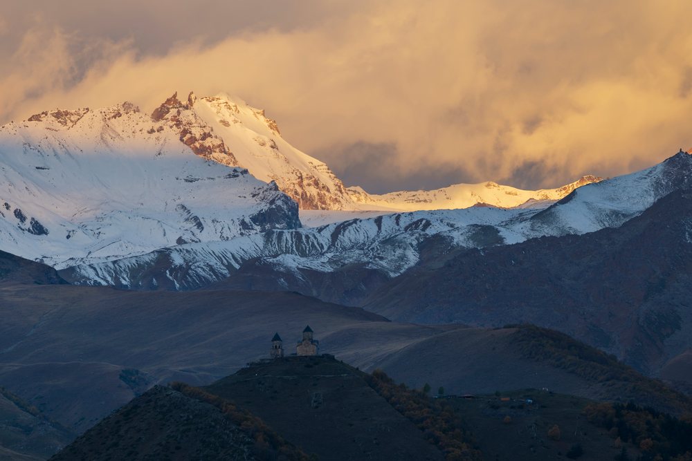 Gergeti Trinity Church sits atop a hill at Dawn, Cityscape, Stepantsminda, Georgia.