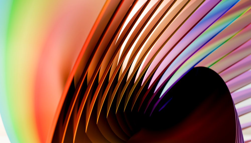 Colorful abstract sculpture with curved metal and rainbow colors reflecting light indoors.