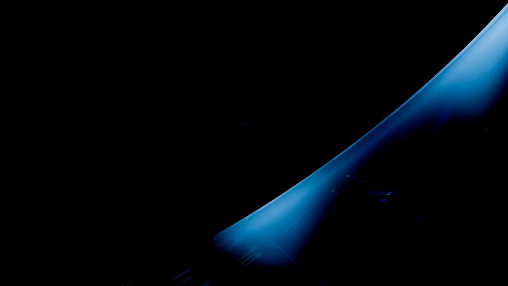 Dynamic stream of blue water flows with visible splashes and droplets against a black background.