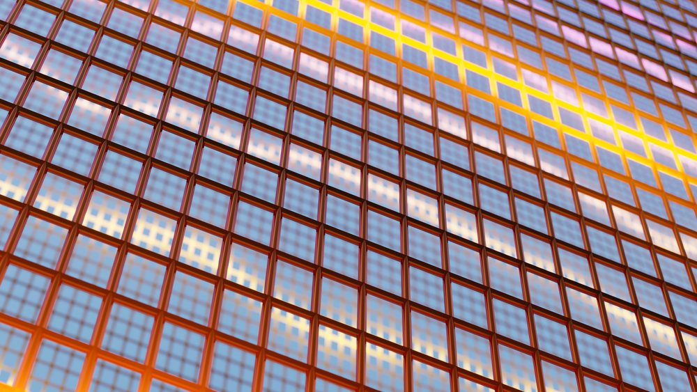 Orange glass blocks arranged in a geometric grid pattern with light reflections creating an abstract architectural texture.