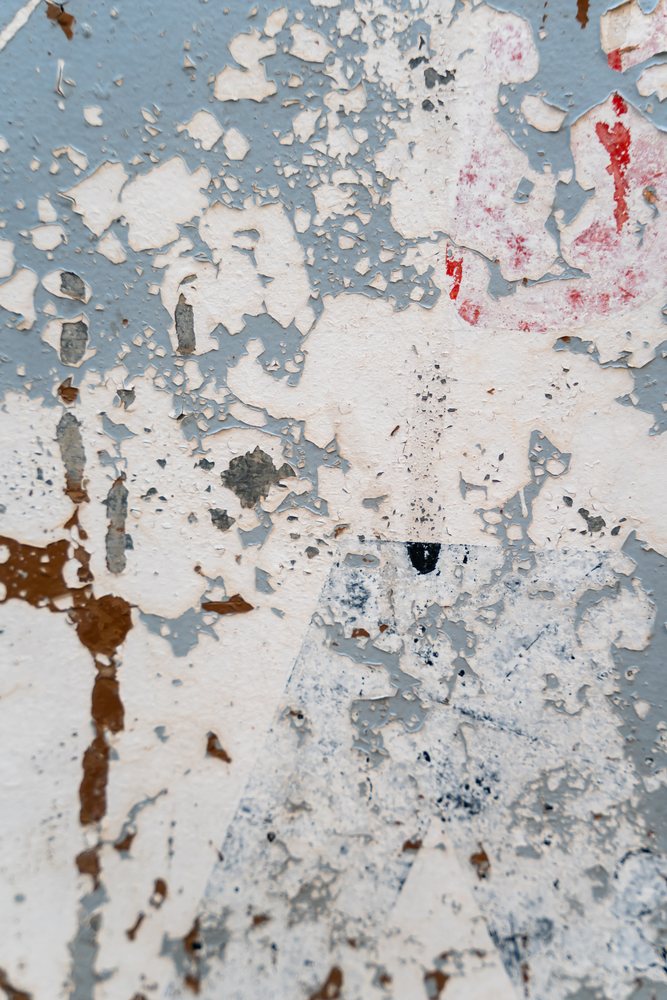 Peeling and weathered multicolored paint with rust spots on an old wall surface, texture, abstract texture, background, wallpaper, Spain.