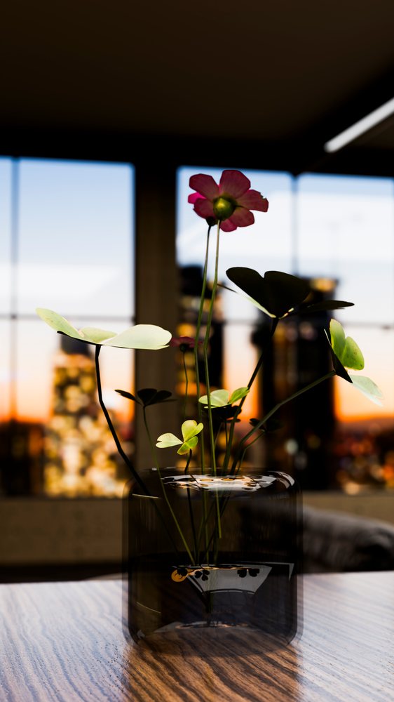 Pink flower petals with green leaves arranged in a glass vase on a wooden table, with a sunset visible through a window behind.