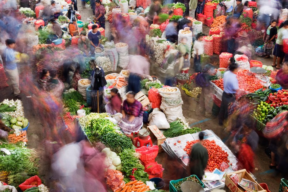 Busy vegetable market, with people shopping among fresh produce stalls, Chichicastenango, Guatemala.