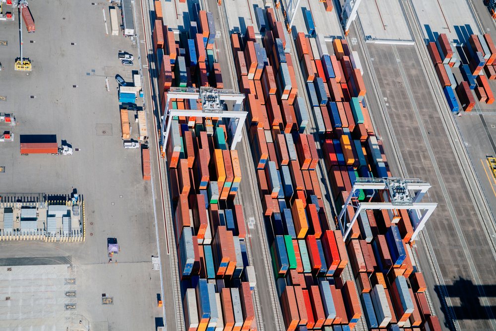 Shipping containers are stacked in rows with container cranes at a major port in Long Beach, California, a major port in Long Beach, CA, USA.