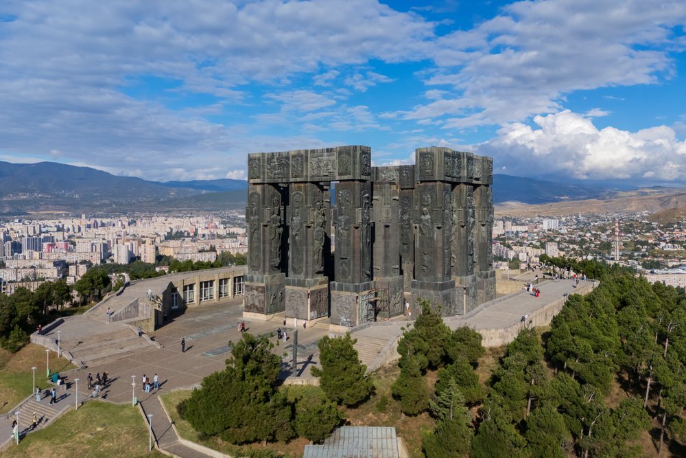 History of Georgia Monument on Keeni Hill overlooking Tbilisi cityscape with mountains and blue sky in the background, Cityscapes.